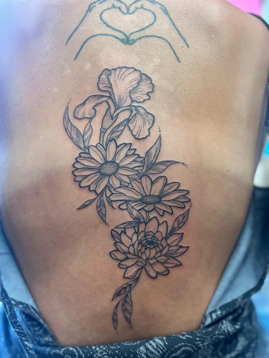 Finished iris, daisy and chrysanthemum spine tattoo